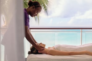 A person receiving a massage in a room with a view of the ocean.