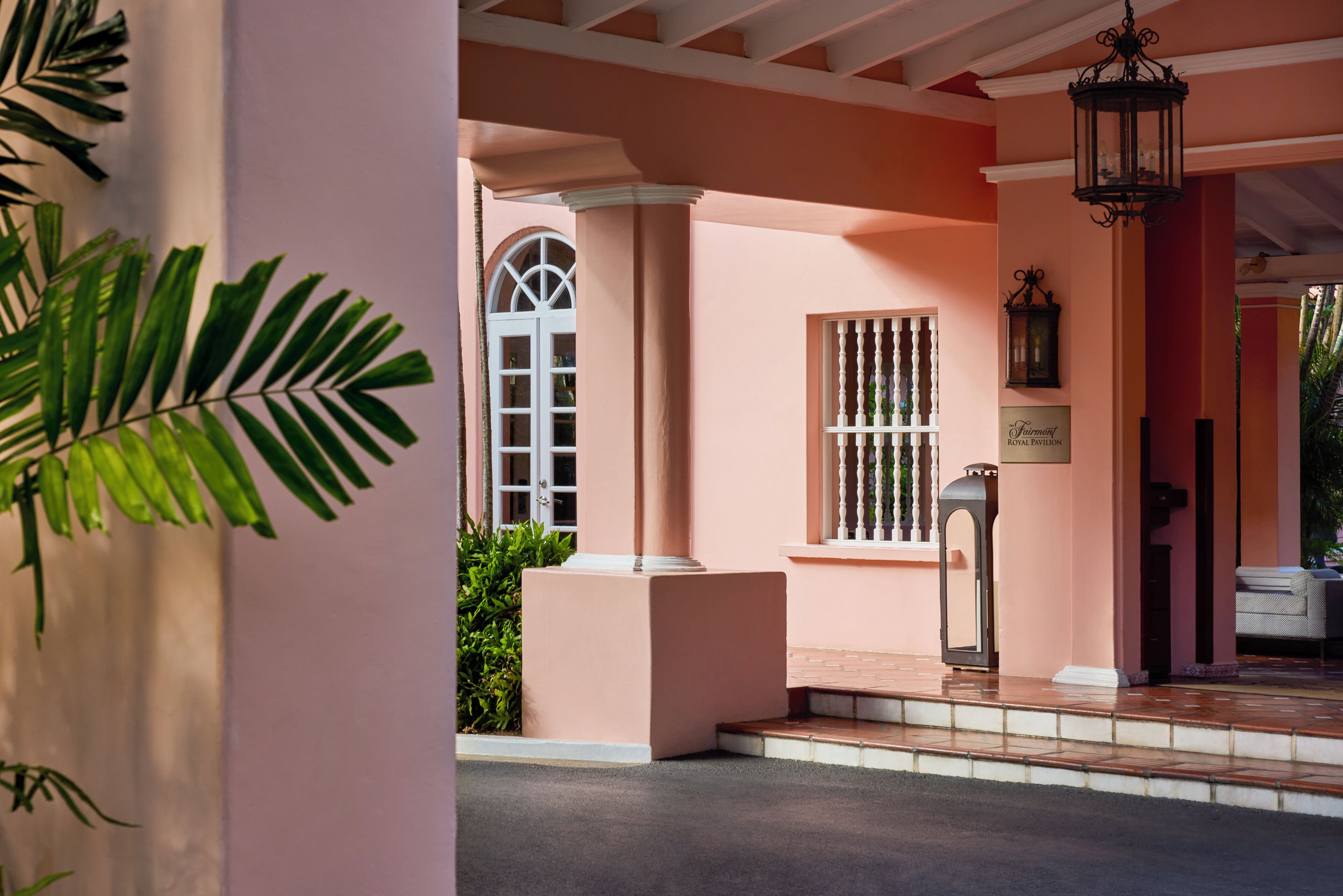 Fachada rosa con puerta blanca, ventana con balaustrada blanca y un cartel que dice 'The Fairmont Royal Pavilion'.
