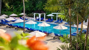A pool area with blue lounge chairs and white umbrellas, surrounded by greenery and a gazebo. - Fairmont Royal Pavilion (Holetown)