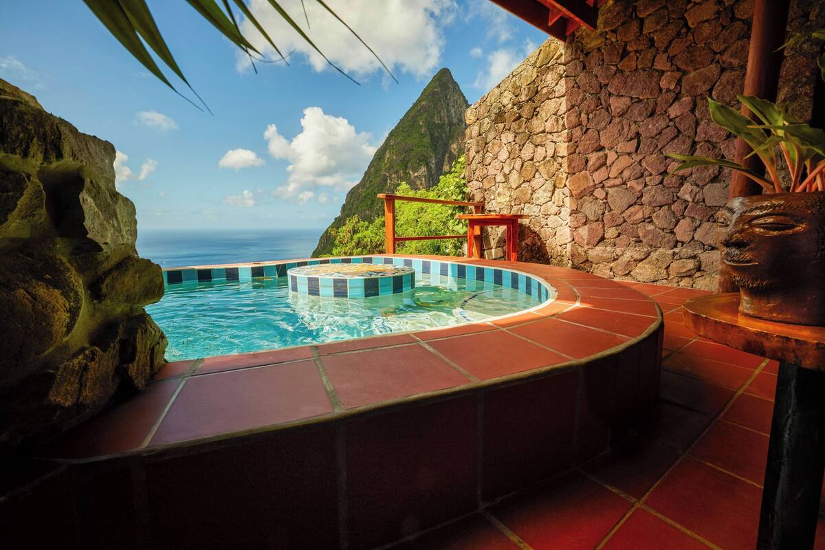 A hot tub with a view of the ocean and a stone wall.