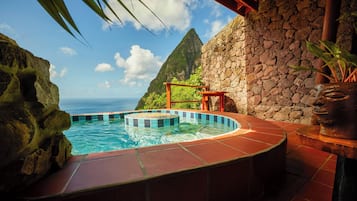 A hot tub with a view of the ocean and a stone wall.