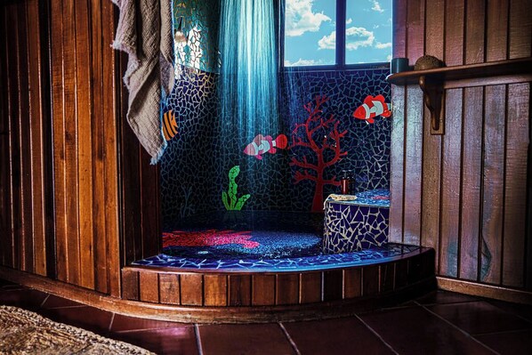 A corner aquarium with a wooden frame, a mosaic backdrop, and a small decorative shelf. - Ladera Resort - Adults Only (Soufrière)