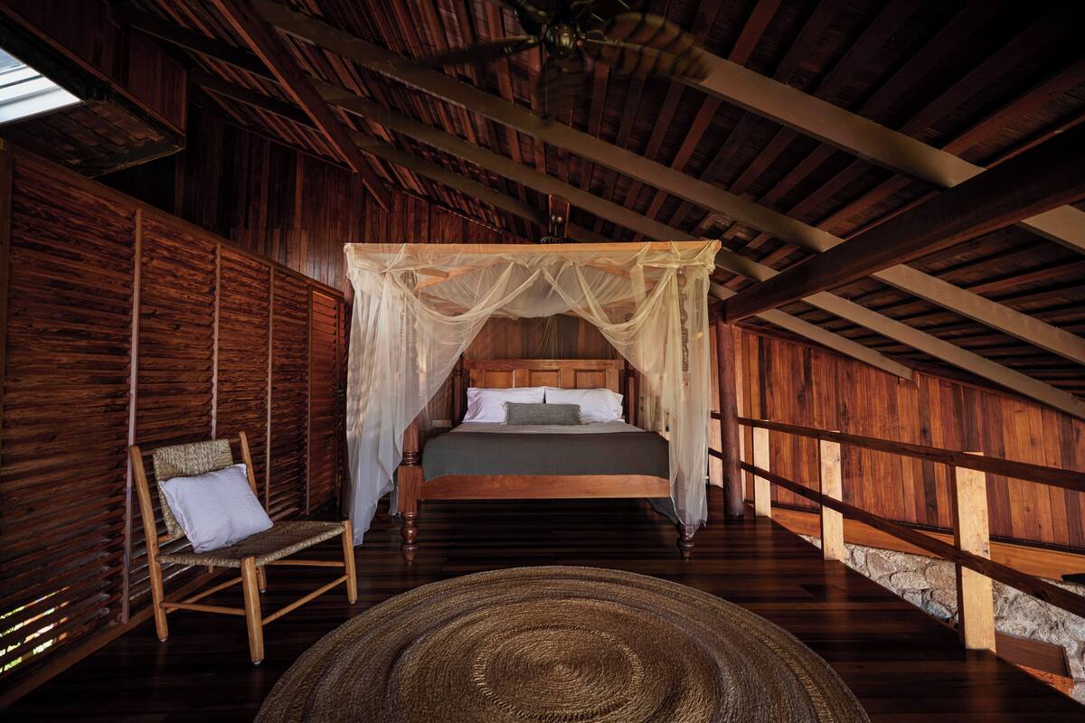 Una habitación de madera con una cama, una silla y un tapiz grande tejido.