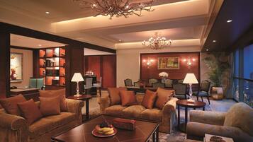 A spacious lobby with a chandelier, seating area, and a view of the city.