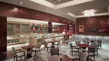 Een moderne hotellobby met een bar, zithoekjes en een grote decoratieve spiegel.