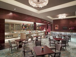 Un moderno vestíbulo de hotel con una zona de bar, arreglos de asientos y un gran espejo decorativo.
