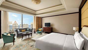 Une chambre d’hôtel avec un grand lit, un canapé, un fauteuil, une petite table et un téléviseur.