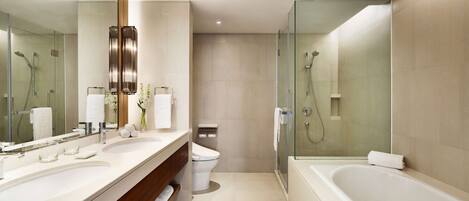 A modern bathroom with a large bathtub, a glass-enclosed shower, and a double sink vanity.