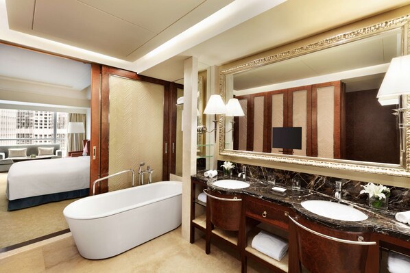 A hotel bathroom with a large bathtub, two sinks, and a large mirror.