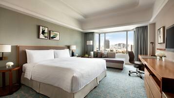 Habitación de hotel con una cama grande, un escritorio, un sofá y vistas a la ciudad.