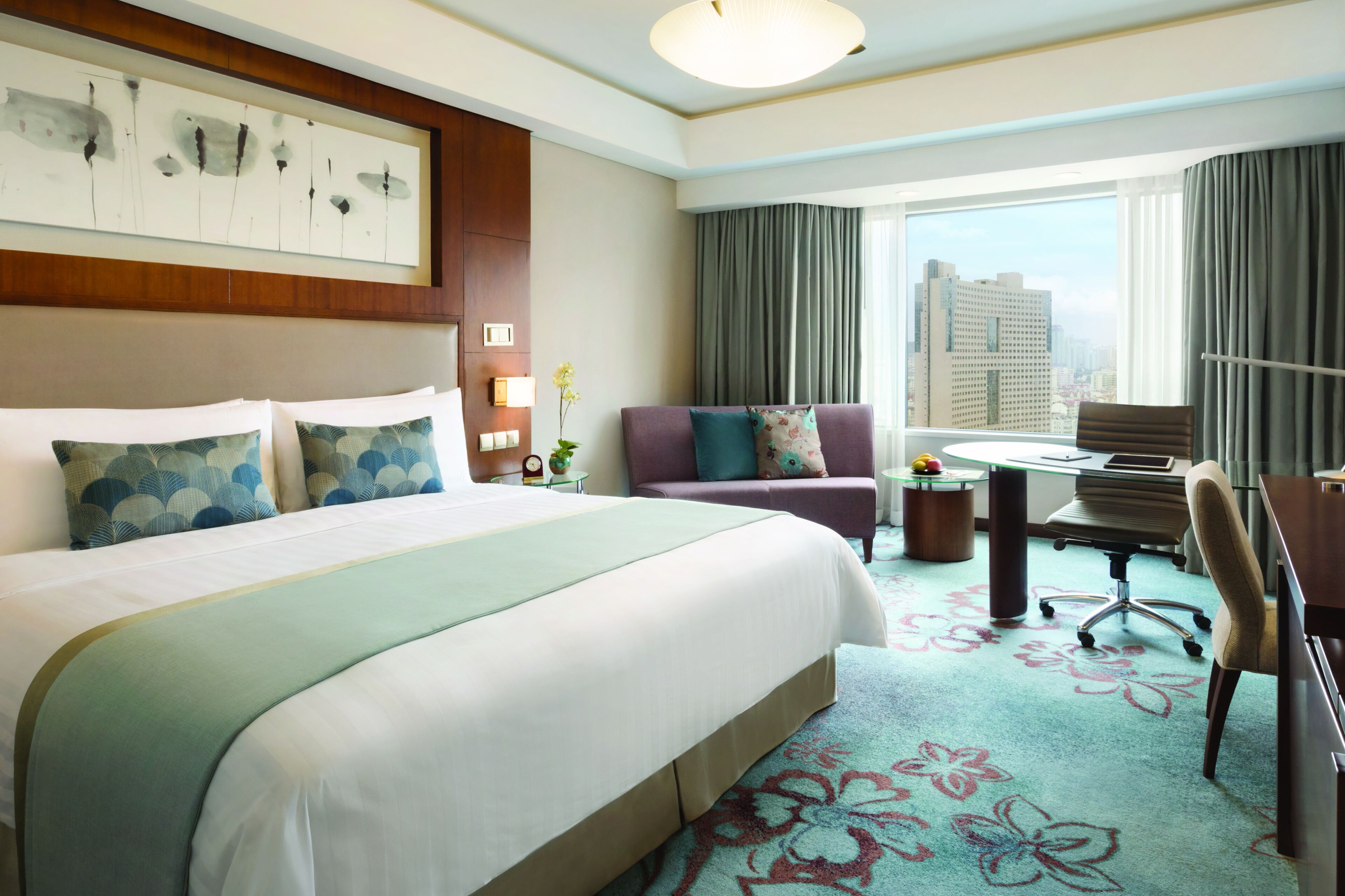 A hotel room with a large bed, a desk, and a view of the city.