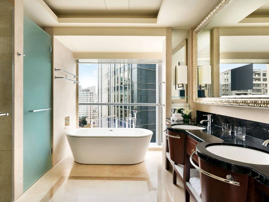 Un baño moderno con una bañera independiente, dos lavamanos y un espejo grande.