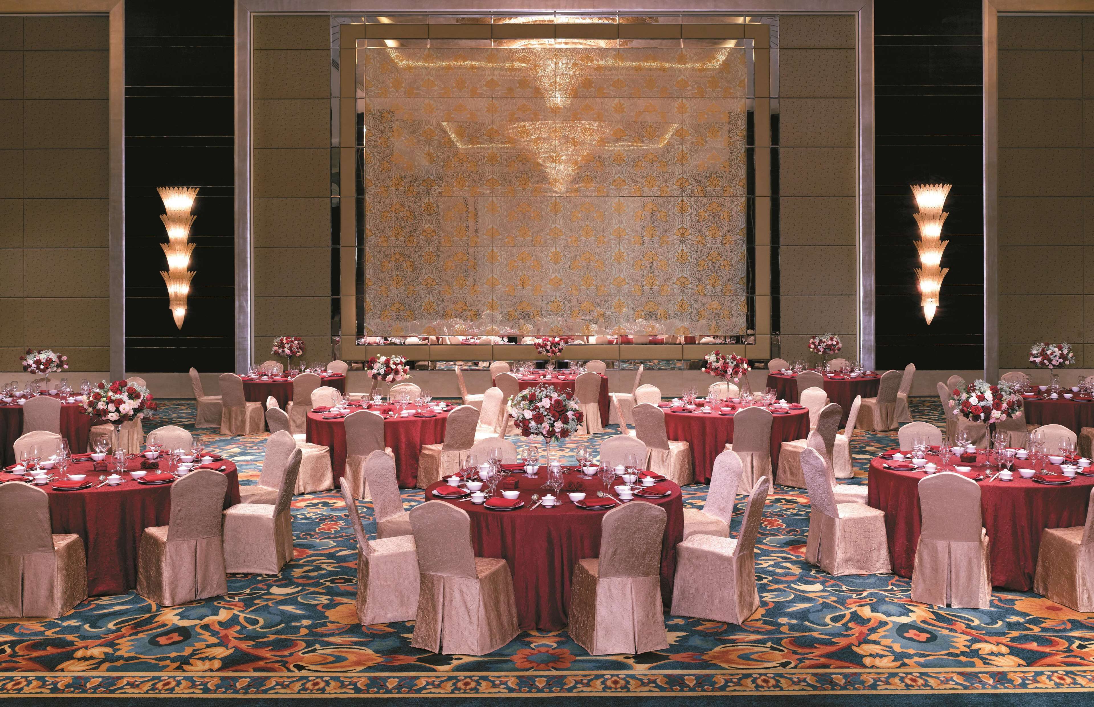 A banquet hall with round tables set for dining, each with chairs and floral centerpieces.