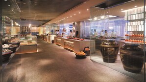 A modern restaurant interior with a long counter, glass display cases, and a variety of food items. - Shangri-La Qingdao (Qingdao)