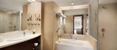 A modern bathroom with two sinks, a bathtub, a glass-enclosed shower, and a large mirror.