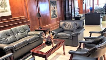 Eine großzügige Lobby mit Ledersofas, einem Couchtisch und einem großen Gemälde an der Wand.