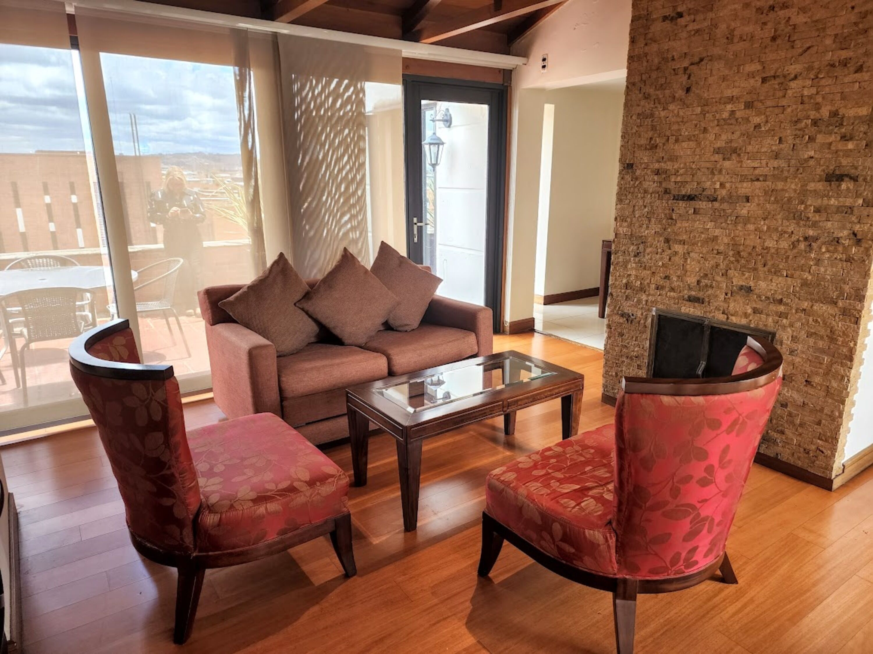 A living room with a sofa, two armchairs, a coffee table, and a fireplace.