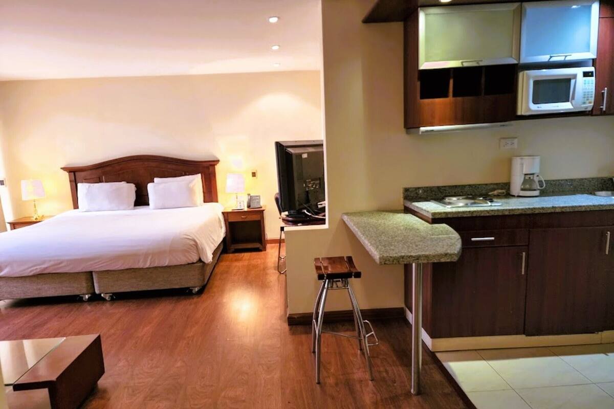 Ein Hotelzimmer mit Bett, Schreibtisch, Stuhl, Fernseher, Mikrowelle und Kaffeemaschine.
