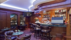 Angolo bar con rivestimenti in legno, un barista e diverse bottiglie e bicchieri sugli scaffali.