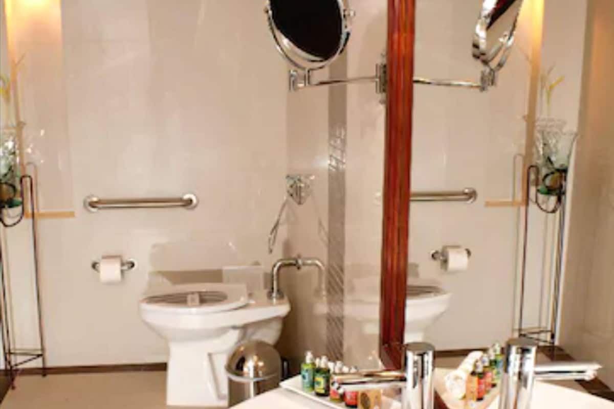 Ein Badezimmer mit einem weißen Waschbecken, zwei Spiegeln, einer Toilette und einem Bidet.