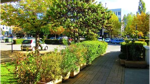 A paved pathway lined with planters and trees, leading to a building with a modern facade. - Aix Hotel (Aix-en-Provence)