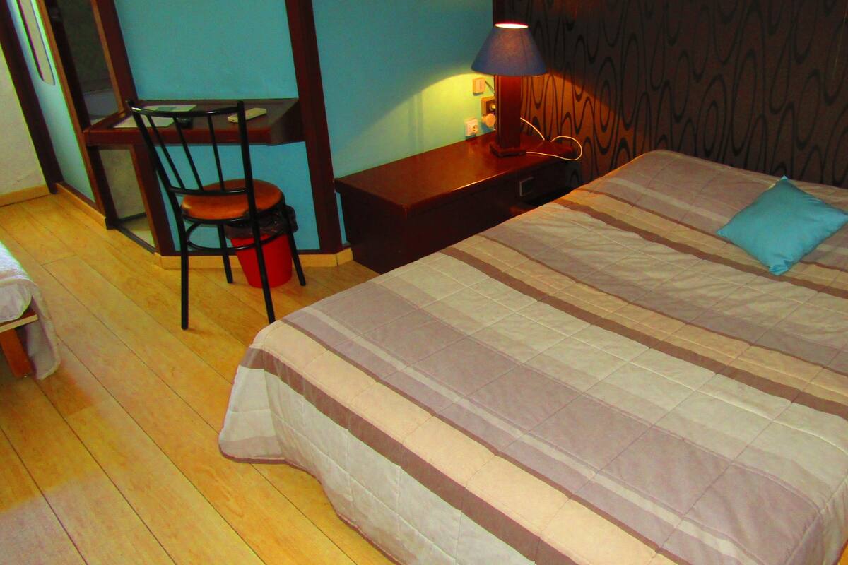 A bedroom with a bed, a desk, and a chair.