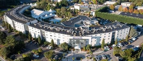 An aerial view of the Westotel hotel with a central courtyard, multiple parking lots, and surrounding greenery.