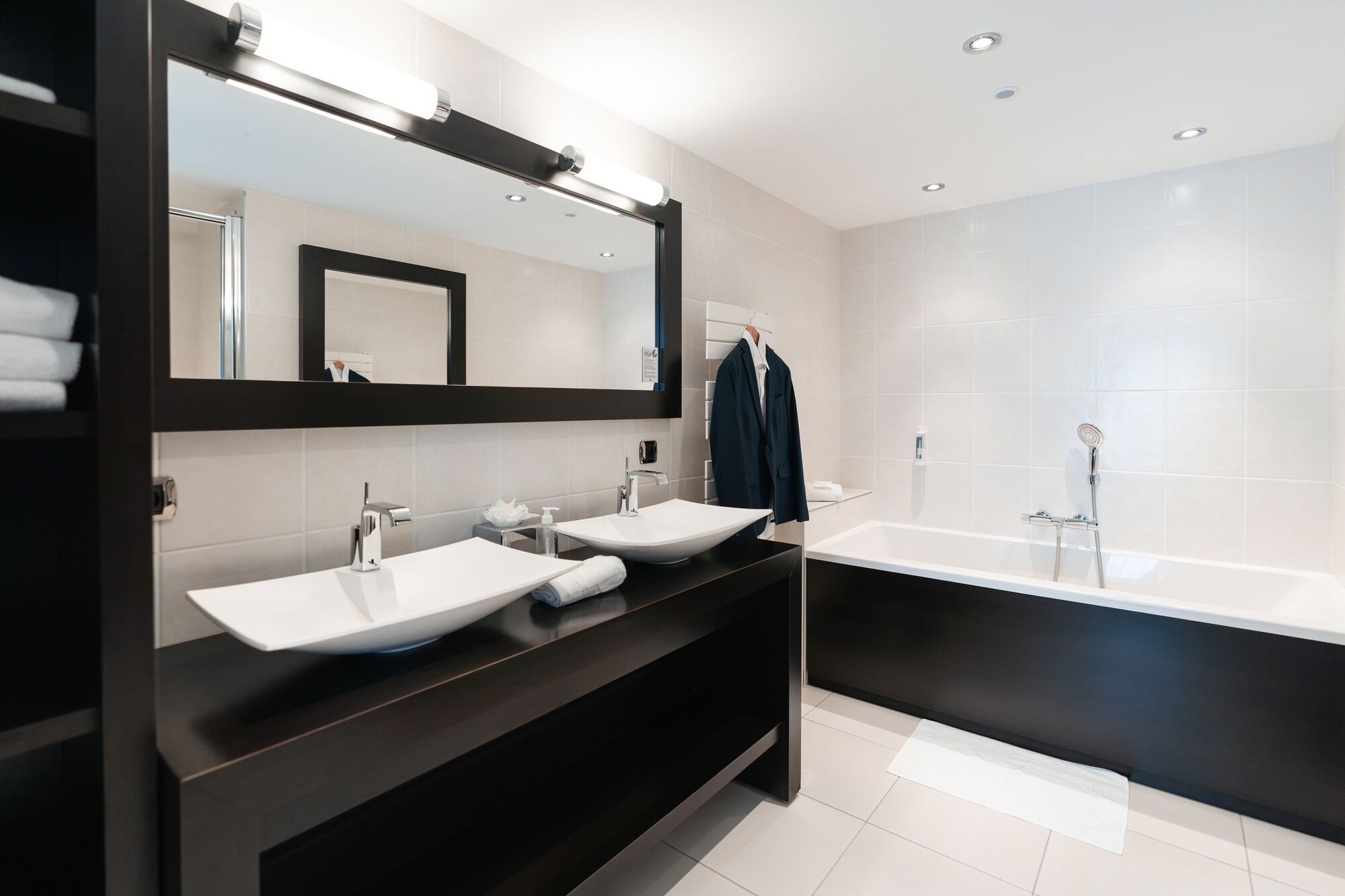 Une salle de bain moderne avec deux lavabos, un grand miroir et une baignoire.