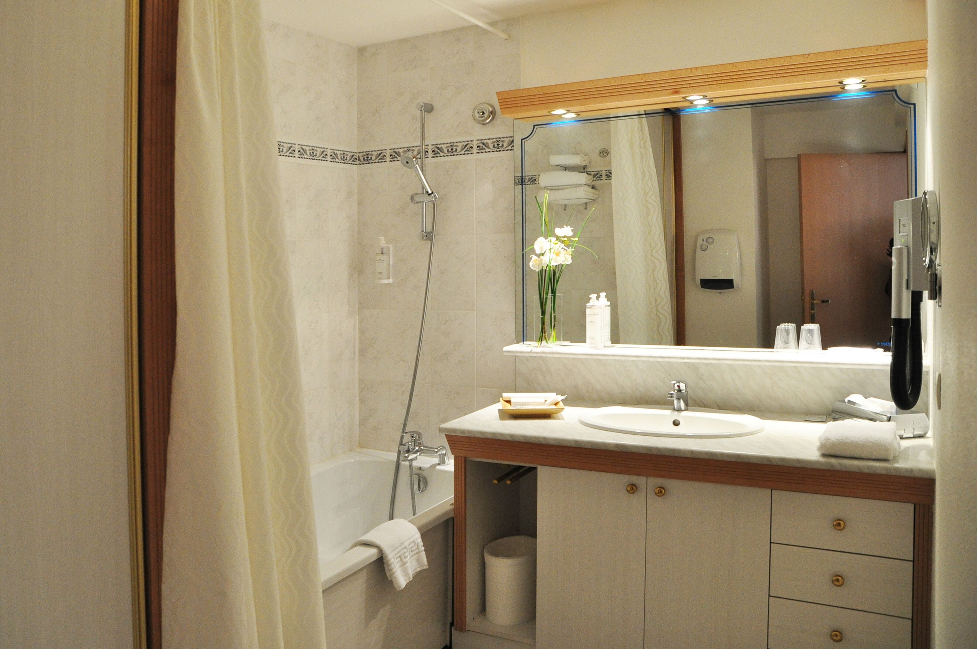 Une salle de bain avec une baignoire, un lavabo, un miroir et une douche.