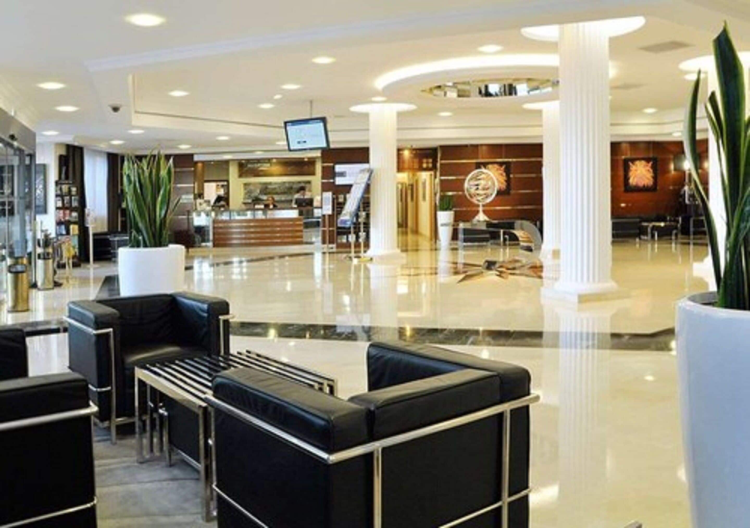 Un moderno vestíbulo de hotel con mostrador de recepción, zona de estar y una gran esfera decorativa.