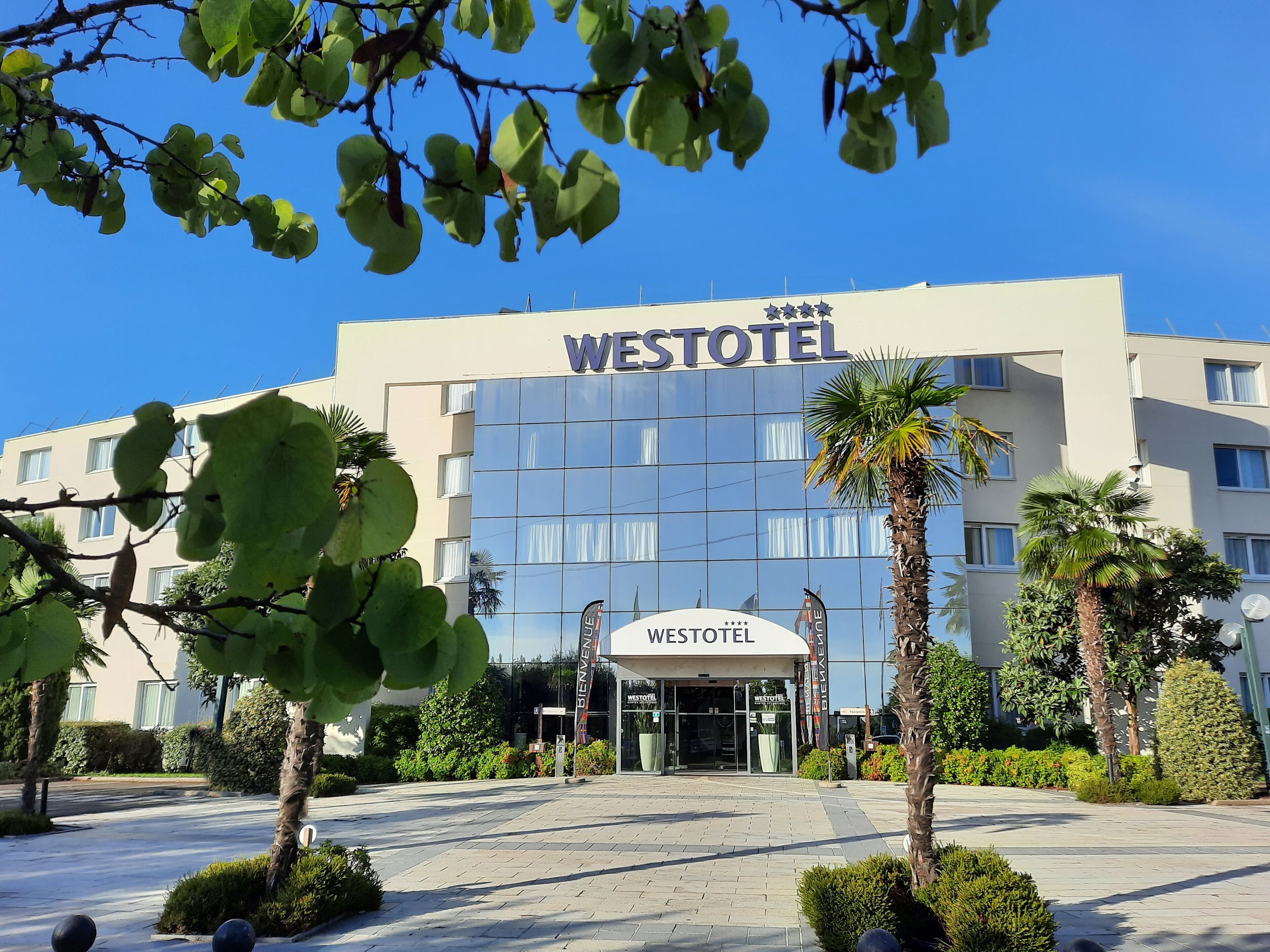 Un edificio Westotel con fachada de vidrio moderna, un área de entrada bien cuidada y zonas verdes circundantes.