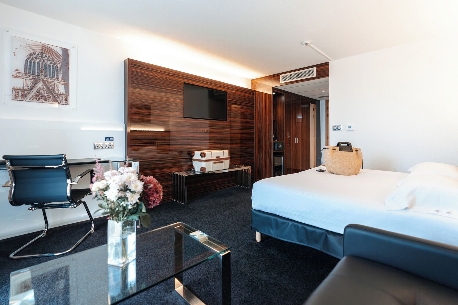 Une chambre d’hôtel avec un lit, un bureau et une chaise, une télévision et un mur recouvert de panneaux en bois.