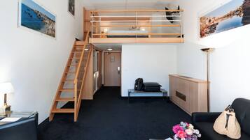 Une petite pièce comprenant un lit superposé, un bureau, une chaise, une lampe et un canapé.