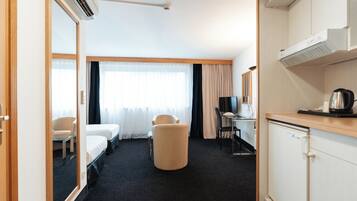 A hotel room with a bed, a desk with a chair, a television, a coffee maker, and a wardrobe.