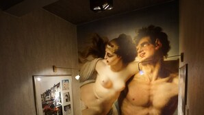 Un escalier orné d’un tableau encadré représentant une vue de la ville et d’une grande affiche mettant en scène deux personnes aux muscles saillants.