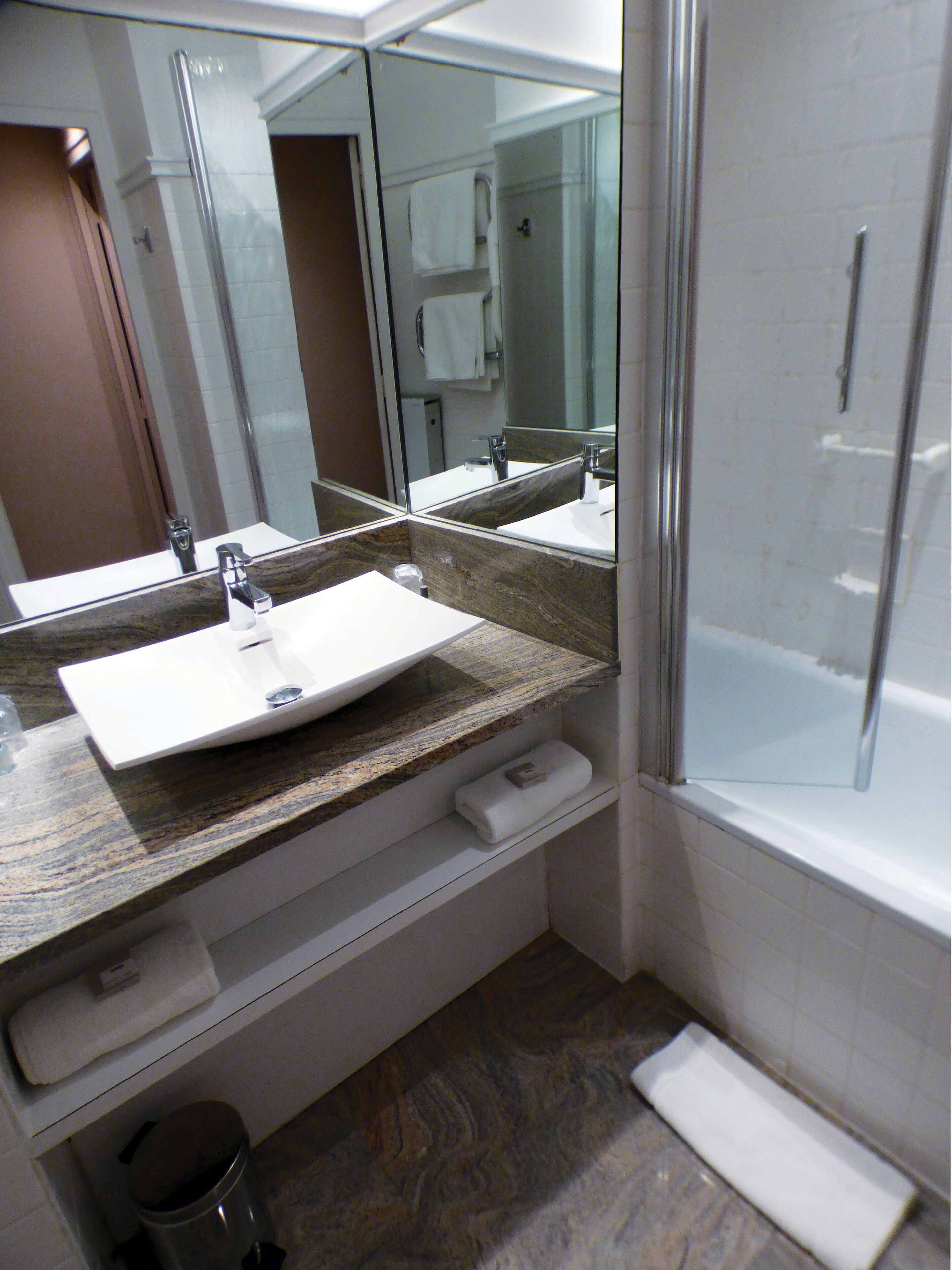 A bathroom with a sink, mirror, and shower.