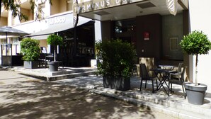 L’entrée d’un hôtel avec un espace extérieur aménagé avec des sièges et des plantes en pot.