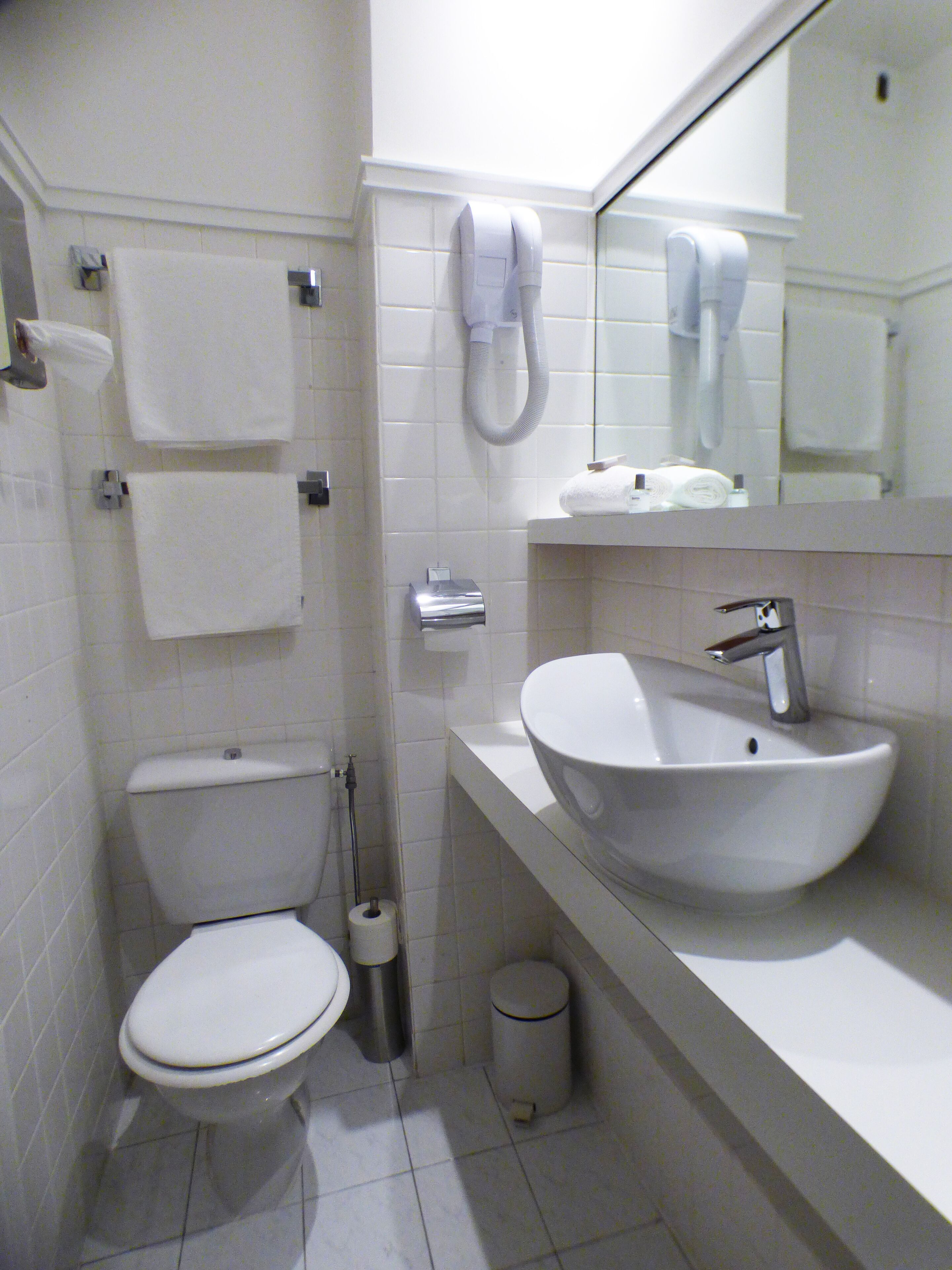 A small bathroom with a toilet, sink, and towel rack.