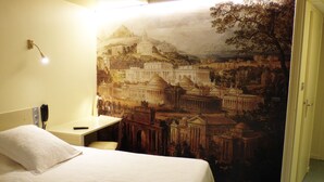 Une chambre d’hôtel avec un grand lit, un bureau et une fresque murale représentant un paysage urbain.