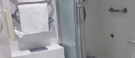 A bathroom with a toilet, a shower, and a sink.