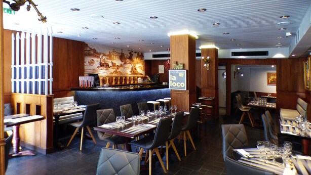 Un restaurant doté d’un bar, de plusieurs tables et chaises, et d’une fresque murale.