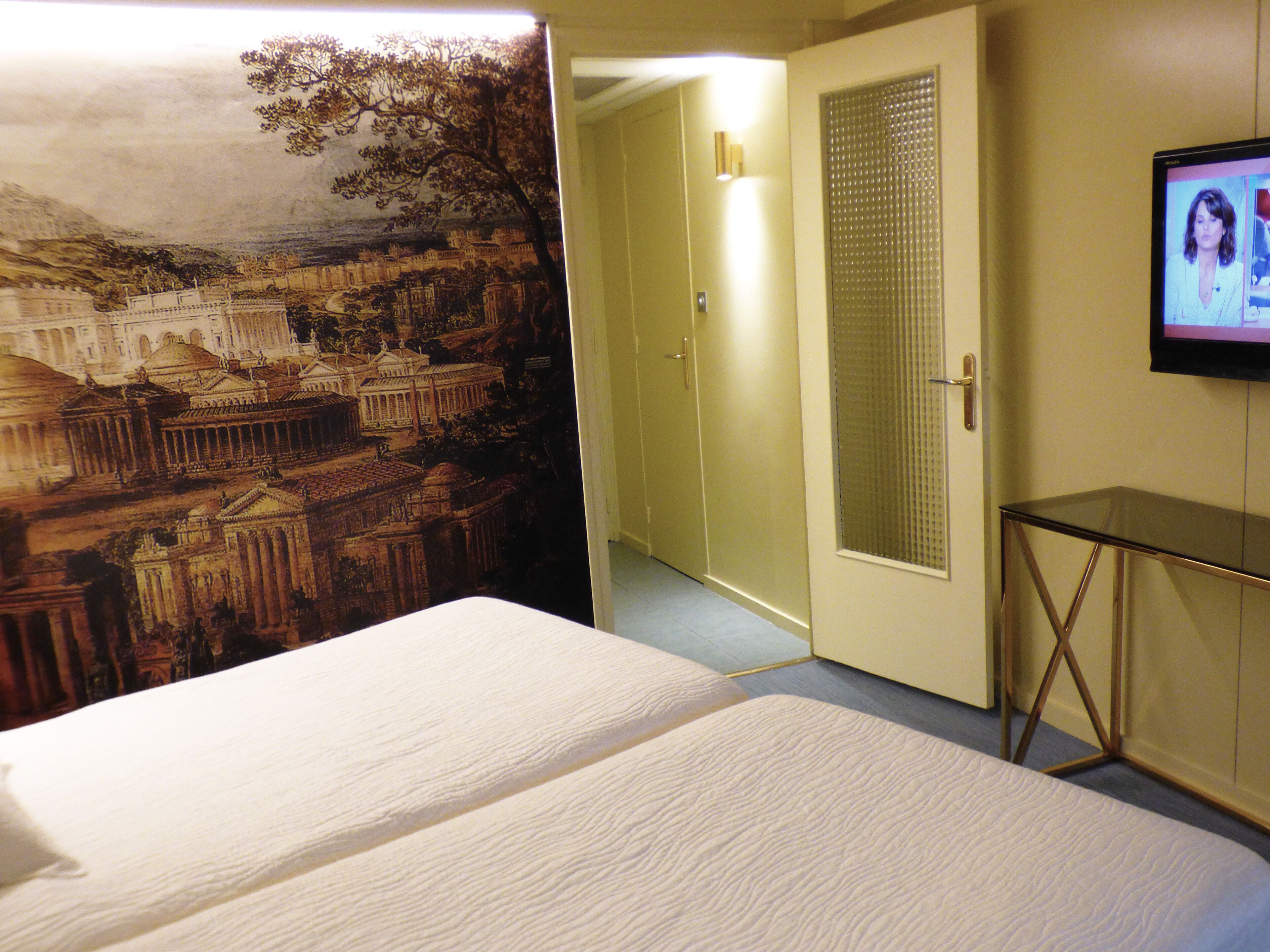 A hotel room with a bed, a television, and a door leading to another room.
