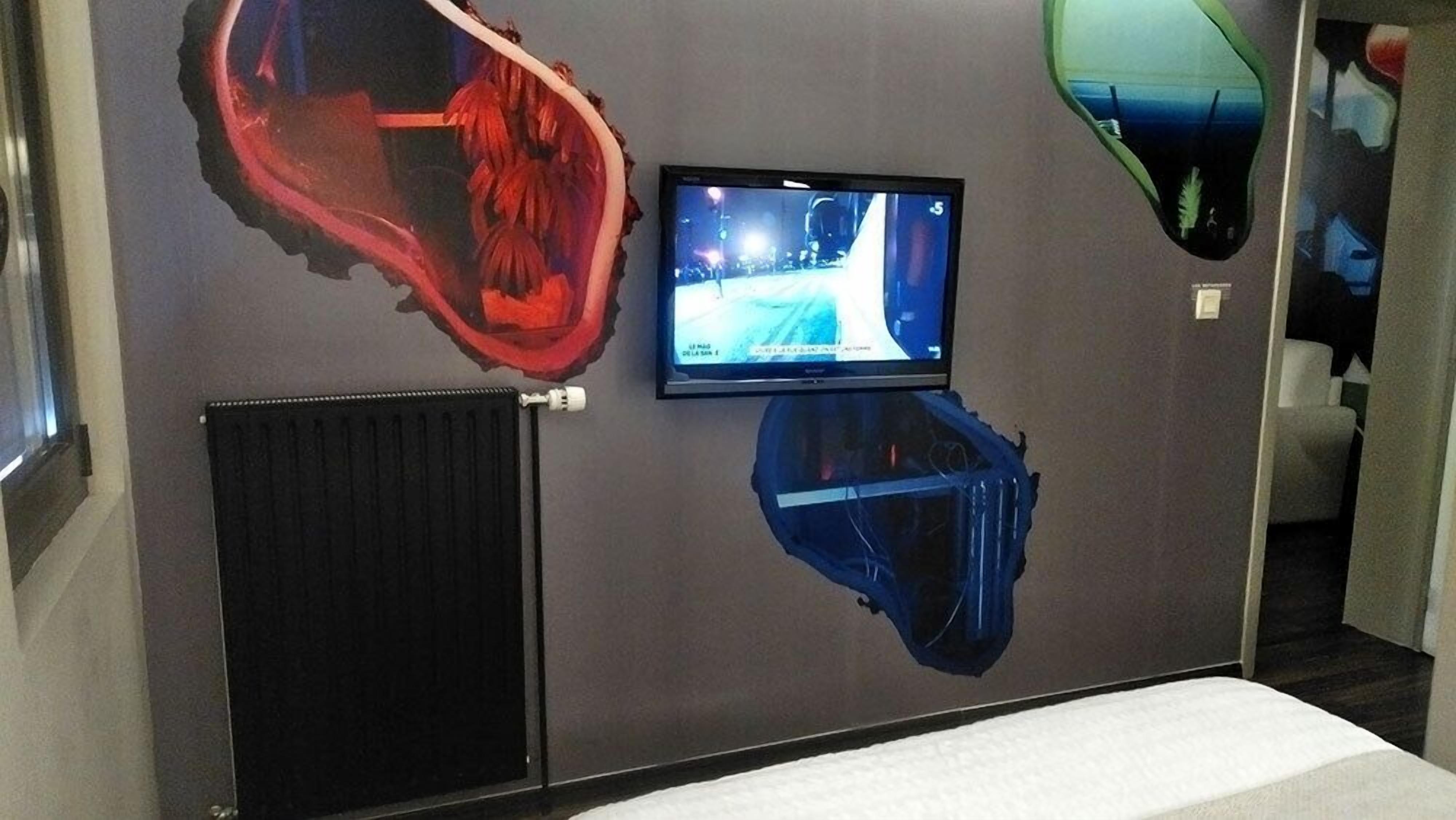 Une pièce avec un grand tableau mural, un téléviseur et un radiateur.