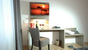 Een hotelkamer met een bureau, stoel, televisie en een bed.
