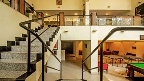 A spacious interior with a staircase leading to a second floor, a billiards table, and a view of the upper level.