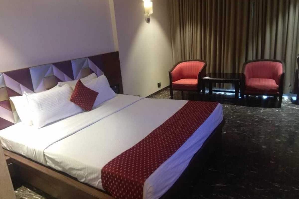 Ein Hotelzimmer mit einem Bett, zwei roten Stühlen, einem kleinen Tisch und einer Wandleuchte.