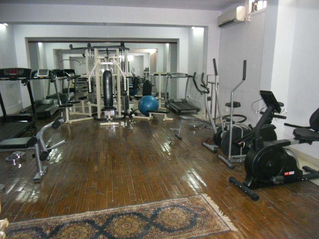 A gym with various exercise equipment, including treadmills, a stationary bike, and free weights.