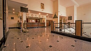 A spacious lobby with a polished floor, a reception desk, and a staircase.