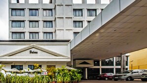 A hotel with a modern architectural design, featuring a prominent entrance with a sign, multiple floors, and a covered parking area.
