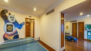 A room with a ping pong table, a large cartoon character mural, and a wooden floor.